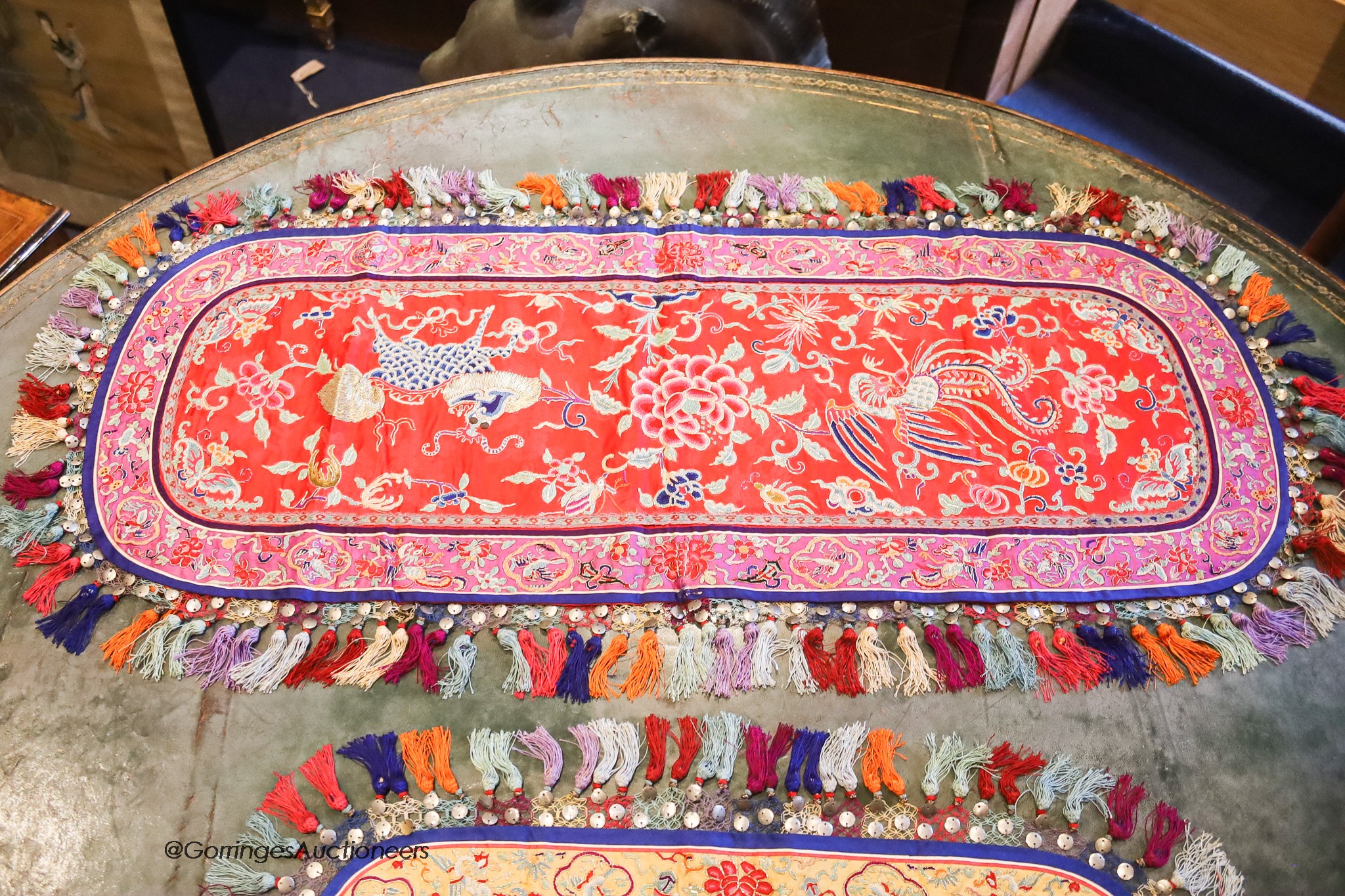 Four 20th century silk embroidered oval table centres edged with multi-coloured tassels, length 96cm